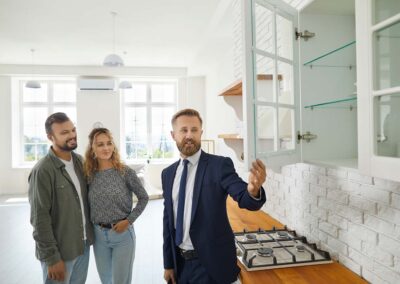 Real estate agent showing buyers kitchen cabinets while giving tour about new house