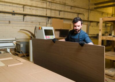 Man holding a wood sheet in a woodshop